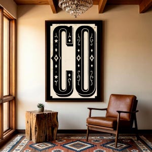 Könnte beinhalten: Ein großes rechteckiges Wandbild mit den fetten schwarzen Buchstaben CO auf cremefarbenem Hintergrund. Die Buchstaben sind mit filigranen weißen Verzierungen, Sternen und Rauten geschmückt und in einem dunkelbraunen Rahmen gefasst.