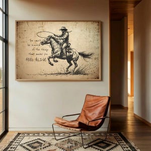 May include: A rectangular wall art print featuring a sepia-toned sketch of a cowboy riding a bucking horse while holding a lasso. The text reads: You can't be scared of the things that make you FEEL ALIVE. The artwork has a distressed, aged paper texture.