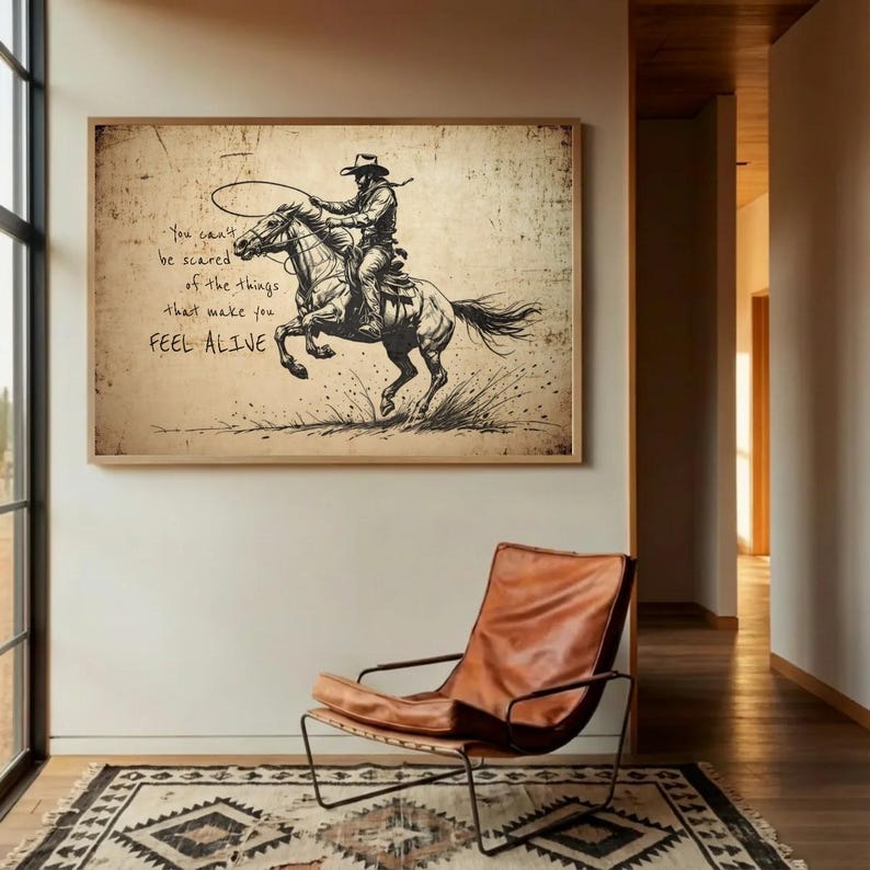 May include: A rectangular wall art print featuring a sepia-toned sketch of a cowboy riding a bucking horse while holding a lasso. The text reads: You can't be scared of the things that make you FEEL ALIVE. The artwork has a distressed, aged paper texture.