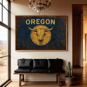 May include: A framed wall art piece featuring the word "OREGON" in gold lettering above a gold bull skull emblem on a blue background. The artwork has a rustic, distressed appearance and is displayed above a black leather bench.