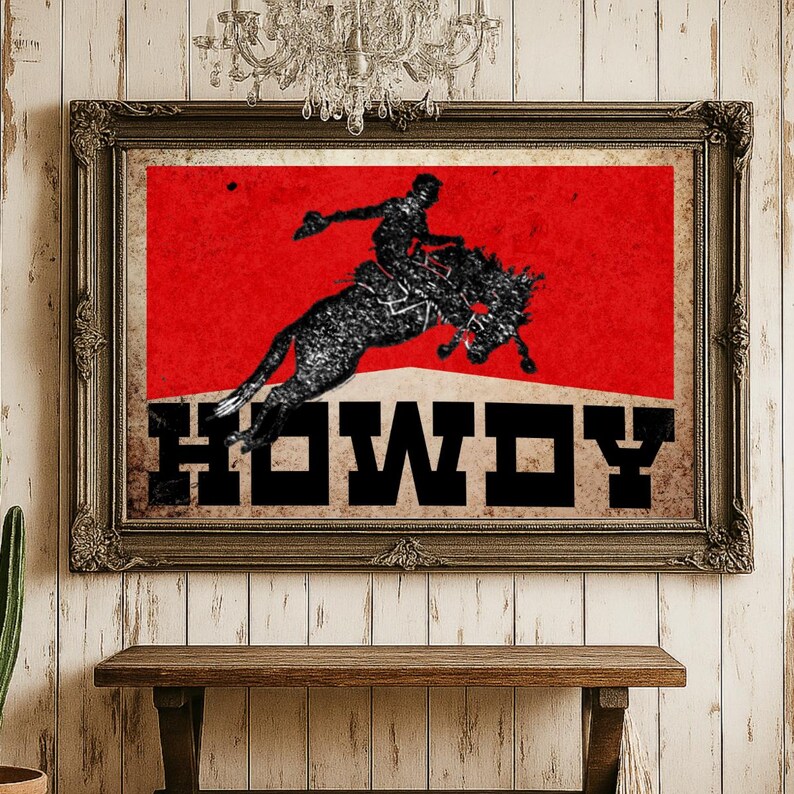 May include: Framed vintage-style print featuring a rodeo cowboy riding a bucking bronco against a red background. The word "HOWDY" is displayed in bold, black letters. The print is in a dark, ornate frame.