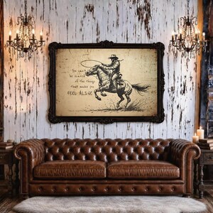 May include: A rectangular framed wall art piece featuring a black ink illustration of a cowboy riding a horse with a lasso. The text reads: You can't be scared of the things that make you FEEL ALIVE. The artwork has a vintage beige paper background.