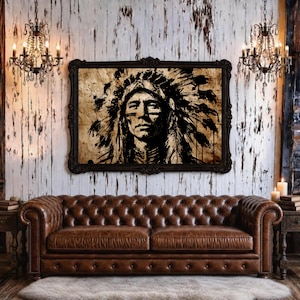 May include: A rectangular framed wall art piece featuring a black ink illustration of a person wearing a traditional feathered headdress, set against a textured tan background, displayed above a brown tufted leather sofa in a room with two chandeliers.