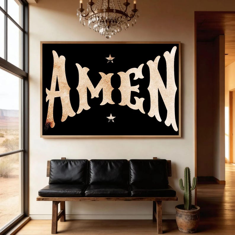 May include: A framed black wall art piece with the word "AMEN" in large, ornate, gold-colored letters. Two small star shapes are above and below the word. The artwork hangs above a black leather bench.