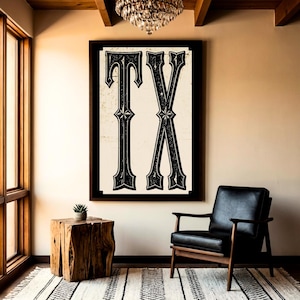 May include: A large rectangular wall art piece featuring the letters TX in a bold, black, decorative serif font with a distressed texture. The letters are centered on a cream-colored background and enclosed within a thick black frame.