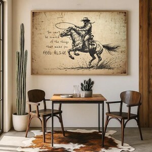 May include: A rectangular wall art print featuring a black ink sketch of a cowboy riding a galloping horse. The text reads: You can't be scared of the things that make you FEEL ALIVE. The background has a distressed, aged paper texture.