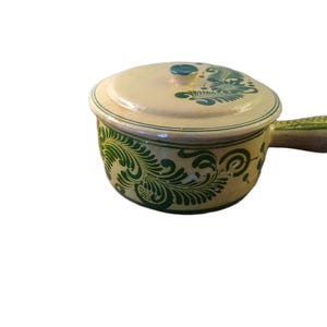 May include: Cream-colored ceramic soup pot with a lid and handle. The pot and lid are decorated with green floral patterns. The handle is short and rectangular. The lid has a small turquoise knob.