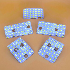 Puede incluir: Cinco placas de luz LED blancas con una cuadrícula de pequeñas luces blancas. Las placas son rectangulares y tienen un color morado claro.