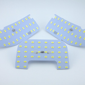 May include: Three white LED light panels with a grid of small white LED lights. The panels are rectangular and have a slightly curved shape.