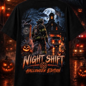 May include: A black t-shirt featuring a graphic of a firefighter standing in front of a fire station at night. The scene includes a full moon, jack-o'-lanterns, and a fire truck. The text reads NIGHT SHIFT HALLOWEEN EDITION in orange lettering.