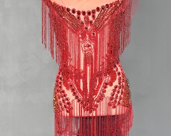 May include: Red beaded fringe top with a sheer fabric base. The top is decorated with red beads and sequins, and has a fringe trim.