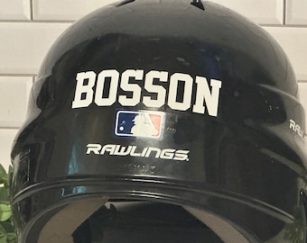 May include: Black baseball helmet with the name "BOSSON" in white block letters. The MLB logo is below the name, and the Rawlings logo is at the bottom. The helmet is glossy and appears new.