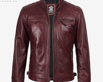 Puede incluir: Una chaqueta de cuero color burdeos oscuro con cuello alzado, cierre de cremallera frontal y paneles acolchados en los hombros. La chaqueta incluye dos bolsillos en el pecho con cremallera, dos bolsillos inferiores y correas laterales.