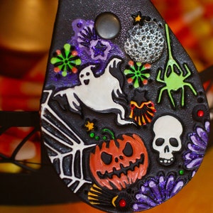 May include: Black leather Halloween-themed keychain with a ghost, spider, pumpkin, skull, and other spooky details.
