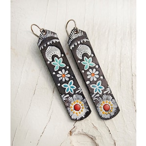 May include: A pair of long, black leather earrings with a white, turquoise and orange floral design.