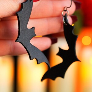 May include: A pair of black leather bat earrings. The earrings are shaped like bats and have a simple, elegant design.