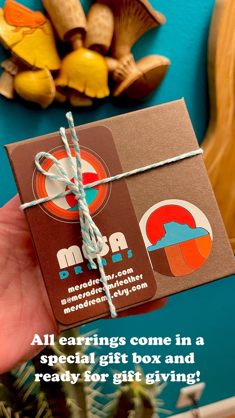 May include: A brown gift box with a white and blue twine bow. The box has a sticker with the text "Mesa Dreams" and a website address. The box is ready for gift giving.