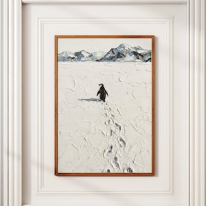 May include: A framed art print featuring a penguin walking across a snowy landscape. The artwork depicts a black and white penguin, with its footprints in the snow. Mountains are visible in the background. The frame is a warm brown color.