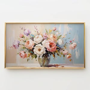May include: A framed floral painting featuring a bouquet of peonies in a glass vase. The artwork showcases a soft color palette of pink, white, and lavender blooms against a light blue and beige background. The frame is gold.