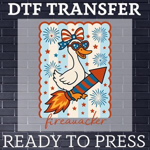 May include: DTF transfer featuring a cartoon goose riding a rocket, wearing heart-shaped sunglasses and a patriotic bow. The design includes fireworks, stars, and the word "fireauacker". Text at the top reads "DTF TRANSFER" and at the bottom "READY TO PRESS".