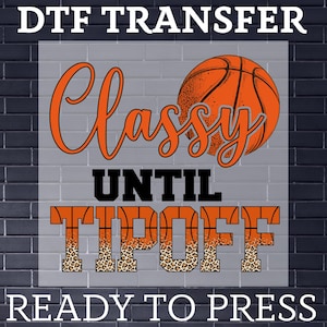 May include: A DTF transfer design featuring the words "Classy Until Tipoff" in orange and black, with a basketball graphic. The word "Tipoff" has a leopard print pattern. The phrase "Ready to Press" is at the bottom.