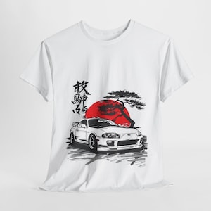 May include: White t-shirt with a Japanese-inspired design featuring a white sports car, a red sun, and a tree. The Japanese text on the shirt reads "秋名山", which translates to "Akina Mountain".