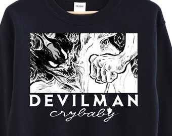 May include: Black sweatshirt with a rectangular graphic featuring a black and white illustration of a monster and a hand. The text "DEVILMAN crybaby" is printed below the graphic in white.