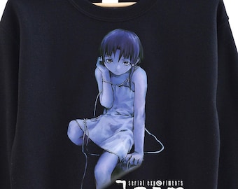 May include: Black sweatshirt featuring a seated anime character in a blue dress, wearing headphones. The graphic includes the text "lain" in white, with additional text below. The sweatshirt is hanging on a wooden hanger.