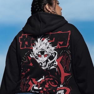 May include: Black hooded sweatshirt featuring a red and white anime-style graphic on the back. The graphic depicts a character with red eyes and spiky white hair. The sweatshirt has a drawstring hood and a kangaroo pocket.