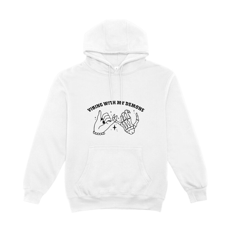May include: White hoodie with a black graphic of two hands holding pinky fingers. The text "Vibing with my demons" is above the graphic.