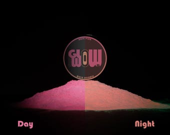 Könnte beinhalten: Produktpräsentation mit einem Haufen rosa Pulver, aufgeteilt in Tages- und Nachtansichten. Das Pulver leuchtet im Dunkeln. Ein kreisförmiger Behälter mit dem Wort "Glow" in rosa Schrift befindet sich über dem Pulver. Die Texte "Day" und "Night" sind ebenfalls sichtbar.