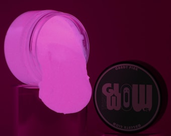 Könnte beinhalten: Ein Glas mit leuchtend rosa Pulver ist umgestoßen, das Pulver quillt heraus. Der Deckel des Glases ist sichtbar, mit den Worten "Candy Pink" und "Glow" darauf gedruckt. Der Hintergrund ist ein tiefes Magenta.