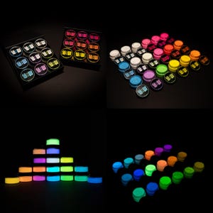 Puede incluir: Una colección de pequeños recipientes redondos con tapas, dispuestos en varias configuraciones. Los recipientes son de una variedad de colores, incluyendo rosa, naranja, amarillo, verde y azul. Cada recipiente tiene una tapa negra con texto blanco y un efecto brillante.