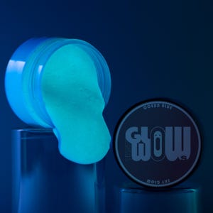 May include: A jar of ocean blue glow-in-the-dark slime pouring out onto a blue surface. The jar has a black label that says "That Glow" and "Sky Glow" with a ghost graphic.