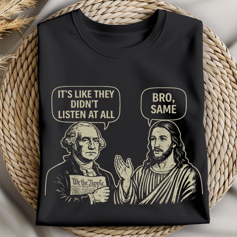 May include: Black t-shirt featuring illustrations of George Washington and Jesus Christ. Washington holds a document that says "We the People" and a speech bubble above him says "It's like they didn't listen at all." Jesus has a speech bubble that says "Bro, Same."