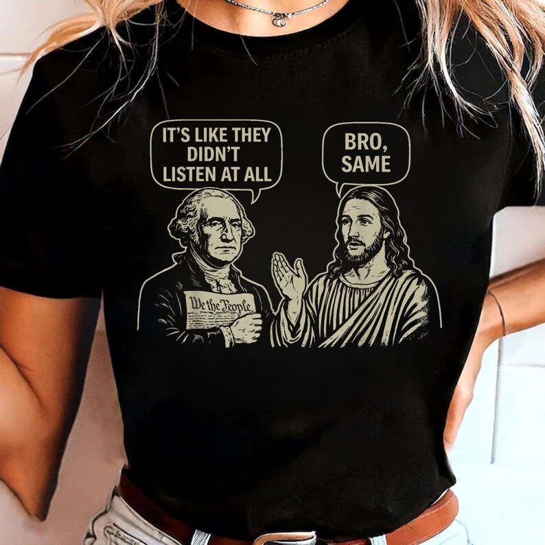 May include: Black t-shirt featuring a graphic of George Washington and Jesus Christ in a humorous conversation. Washington holds a document that reads "We the People." Speech bubbles above them say "It's like they didn't listen at all" and "Bro, Same."