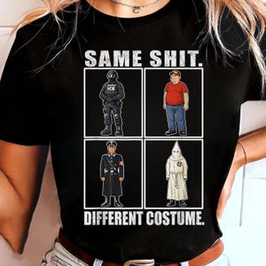 May include: Black t-shirt with the text "SAME SHIT. DIFFERENT COSTUME." The shirt features a graphic with four panels depicting figures in different uniforms and costumes, including a police officer, a man in a red shirt, a Nazi officer, and a KKK member.
