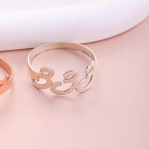 Puede incluir: Un anillo de plata con la palabra "333" escrita en una fuente estilizada.