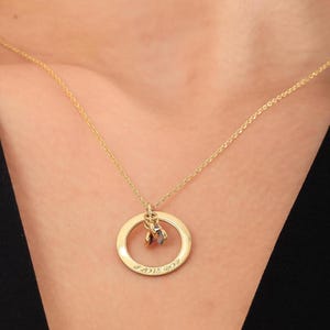 May include: A gold necklace with a circle pendant that says "I love you" and has two small stones hanging from it.