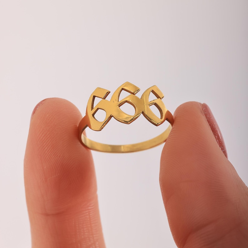 Puede incluir: Anillo de oro con el n&uacute;mero 666 en una fuente estilizada.