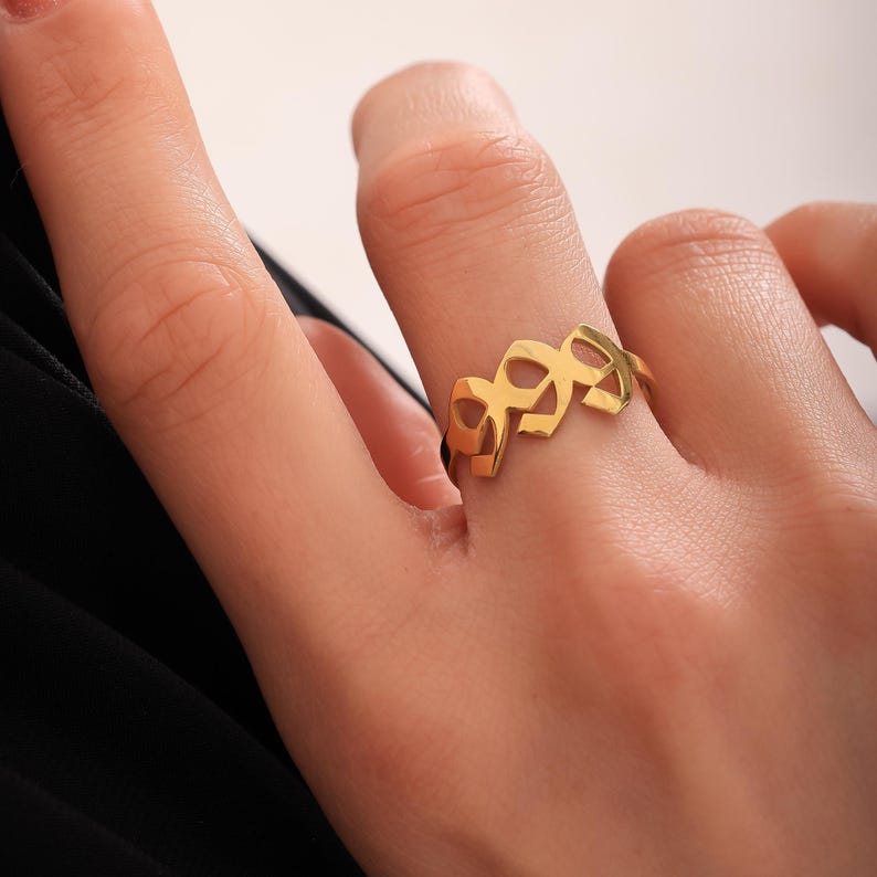 Puede incluir: Un anillo dorado con un nombre escrito en cursiva.