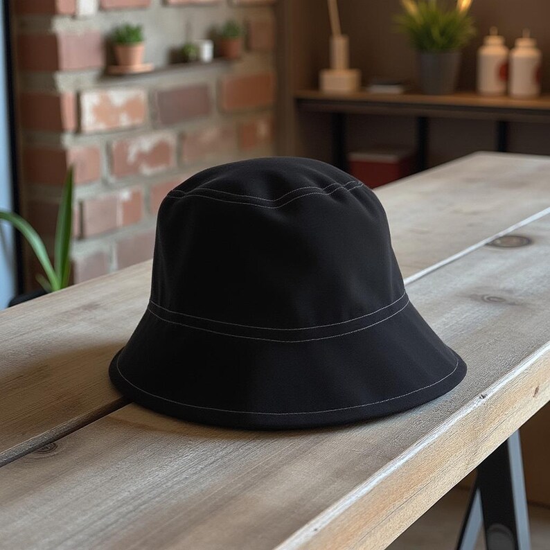 May include: A black bucket hat with a white stitch detail around the brim.
