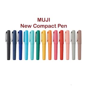 Puede incluir: Una colección de bolígrafos compactos Muji New en varios colores, incluyendo negro, azul, turquesa, verde, amarillo, naranja, rosa, rojo y gris. Cada bolígrafo tiene una tapa a juego y un clip plateado. El texto "MUJI New Compact Pen" se muestra encima de los bolígrafos.