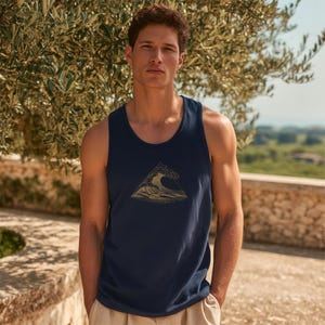 May include: A navy blue sleeveless tank top featuring a centered graphic of a stylized ocean wave enclosed within a triangle outline. The graphic is rendered in a light gold or tan color, contrasting against the dark fabric of the garment.
