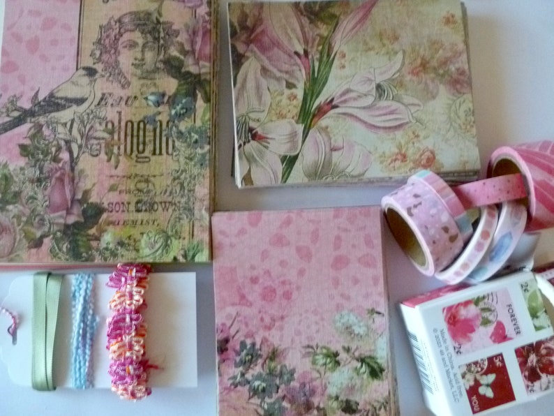 May include: A collection of pink and green floral patterned paper, pink patterned paper, and washi tape rolls. The washi tape rolls are in various colors and patterns. The paper is perfect for scrapbooking, card making, and other craft projects.