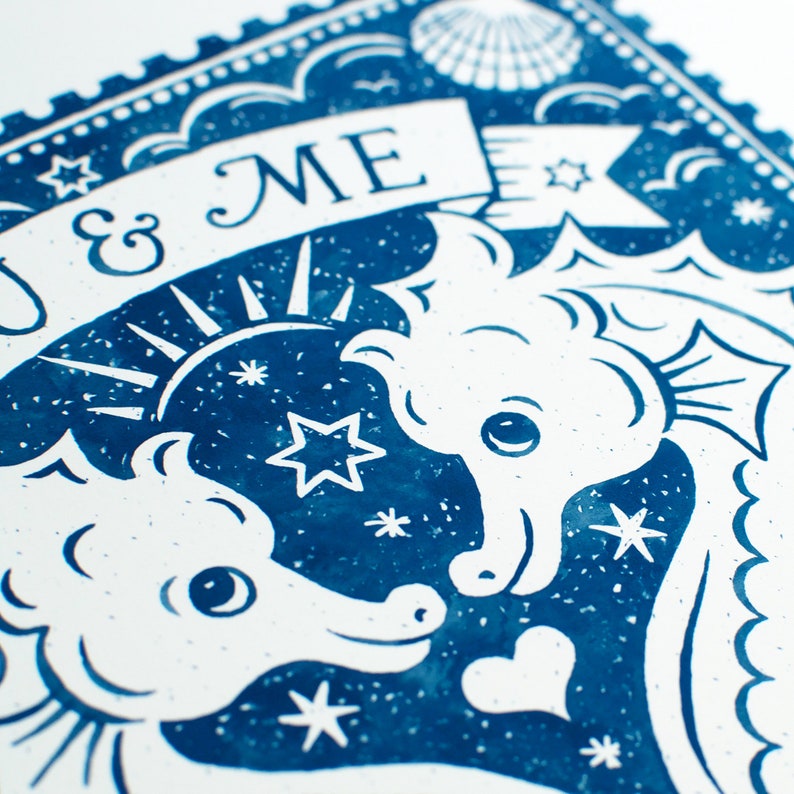 K&ouml;nnte beinhalten: Eine blaue und wei&szlig;e Illustration von zwei Seepferdchen, die sich gegen&uuml;berstehen, mit einem Banner, auf dem "You & Me" steht. Der Hintergrund ist ein blauer Sternenhimmel mit einer wei&szlig;en Muschel in der oberen Ecke.