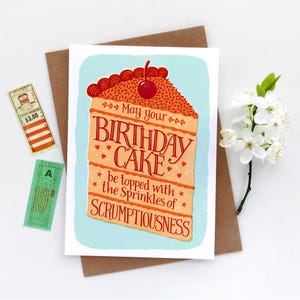 May include: A birthday card with a colorful illustration of a slice of cake with a cherry on top. The text on the card reads "May your birthday cake be topped with the sprinkles of scrumptiousness."