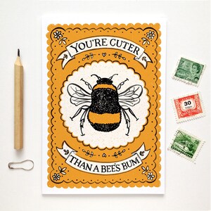 May include: A yellow card with a black and yellow bumblebee illustration and the text "YOU'RE CUTER THAN A BEES BUM" in black lettering.