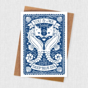 K&ouml;nnte beinhalten: Eine blaue und wei&szlig;e Gru&szlig;karte mit einem Vintage-Design, das zwei Seepferdchen zeigt, die eine Herzform bilden. Der Text "You & Me & The Deep Blue Sea" ist auf der Karte gedruckt.
