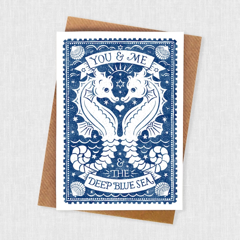 K&ouml;nnte beinhalten: Eine blaue und wei&szlig;e Gru&szlig;karte mit einem Vintage-Design, das zwei Seepferdchen zeigt, die eine Herzform bilden. Der Text "You & Me & The Deep Blue Sea" ist auf der Karte gedruckt.